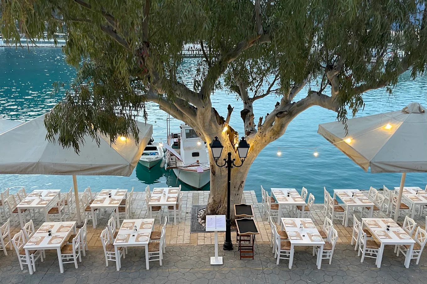 Waterfront restaurant tables beside Vasiliki harbour in Lefkada at dusk
